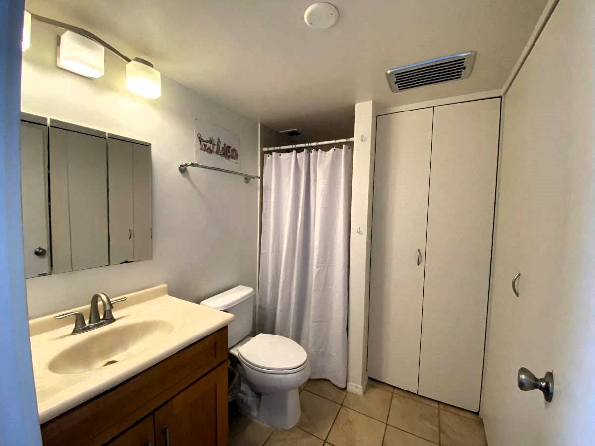 A bathroom with a toilet, sink, and shower curtain.